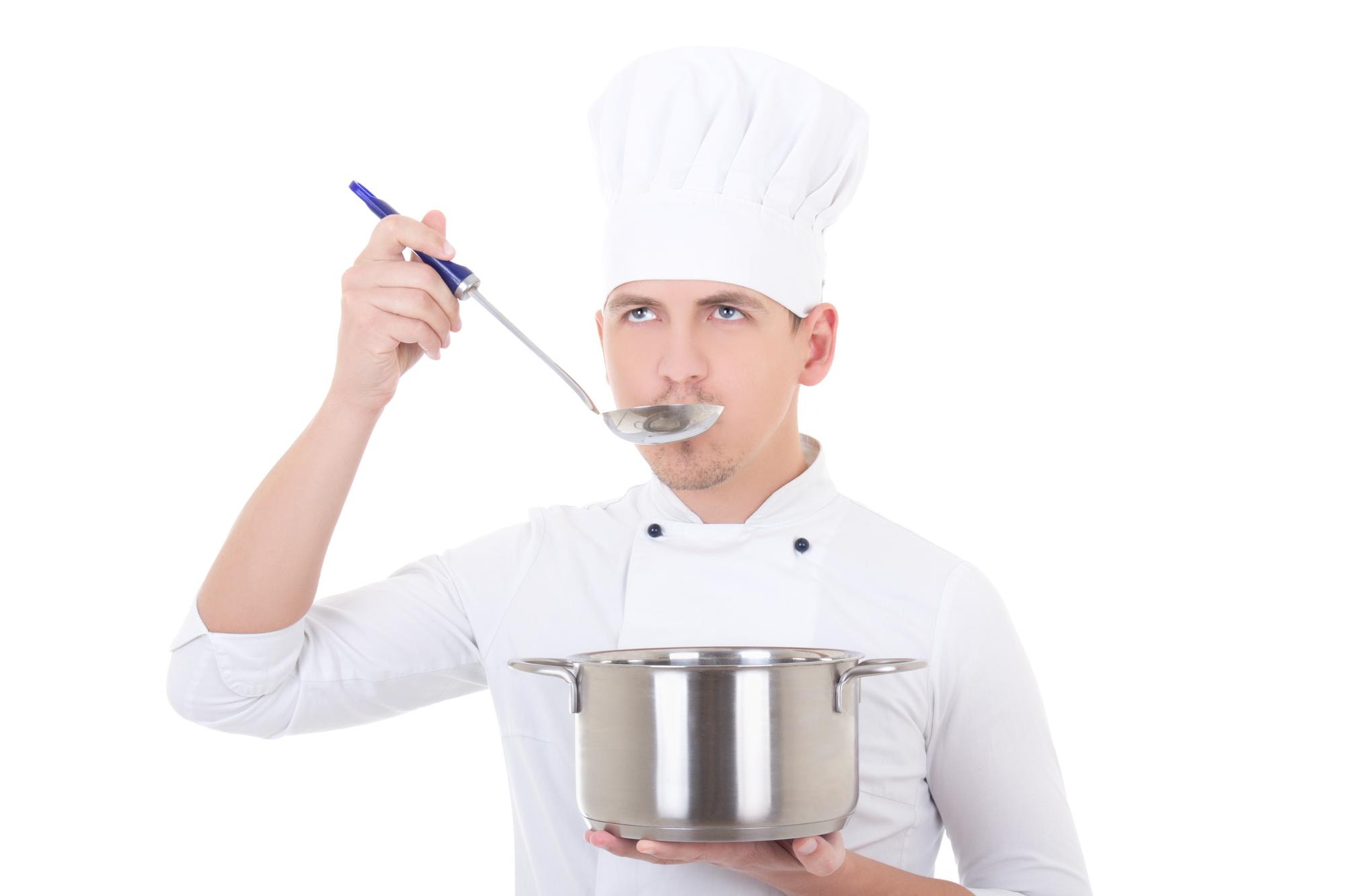 Chef testing sauce in stainless saucepan